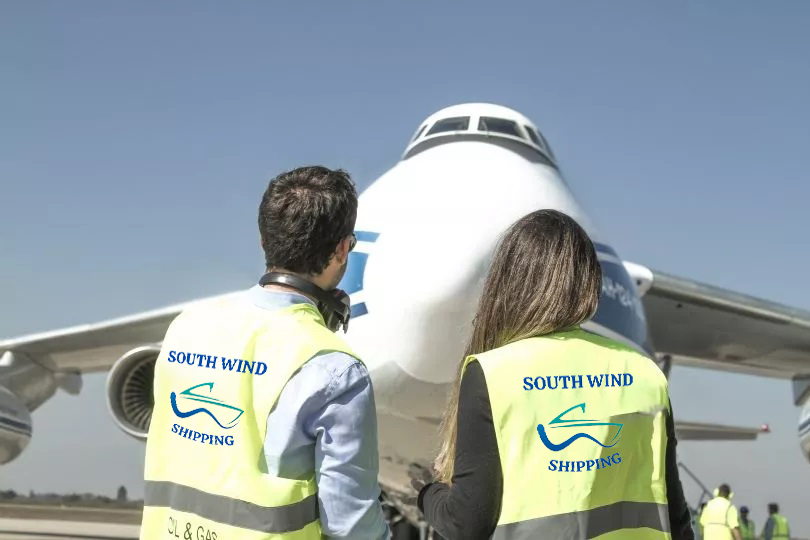 Two South Wind employees on a runway looking at a plane